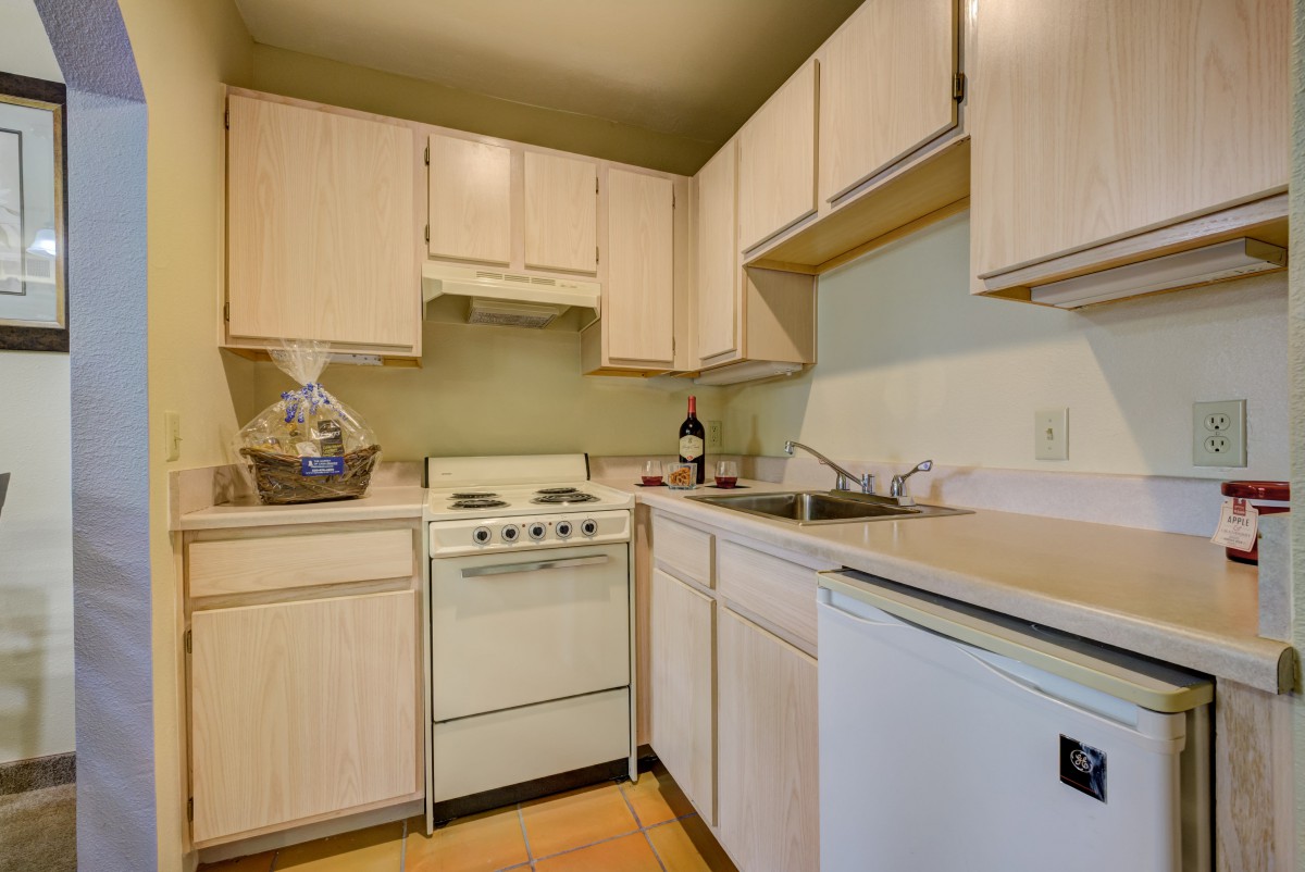 A compact kitchen with wooden cabinets and basic appliances.