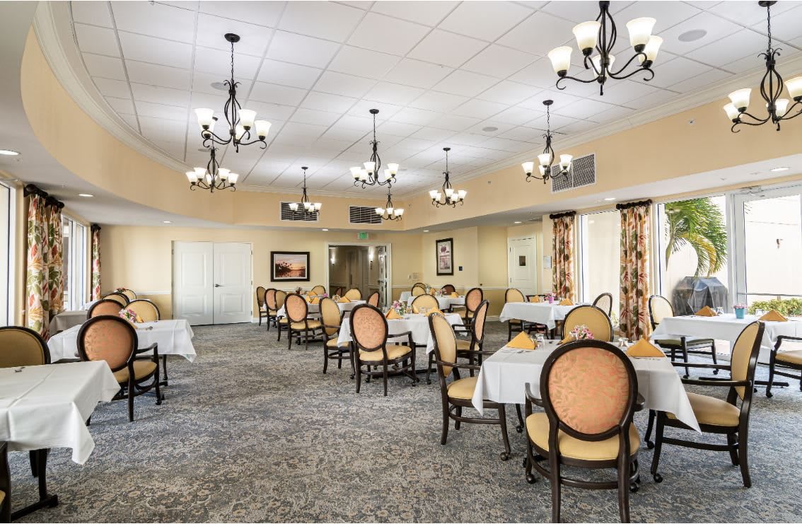 An elegant dining room with chandeliers and neatly arranged tables and chairs.