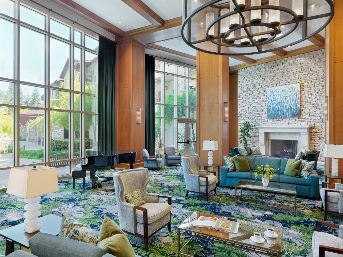 A luxurious hotel lobby featuring elegant seating, a grand chandelier, and a fireplace.