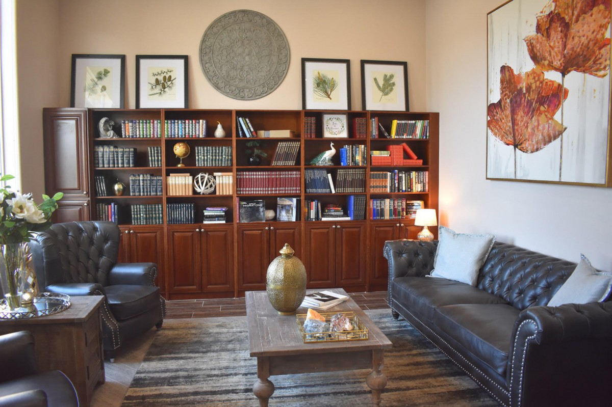 A cozy library room with bookshelves, leather seating, and a coffee table.
