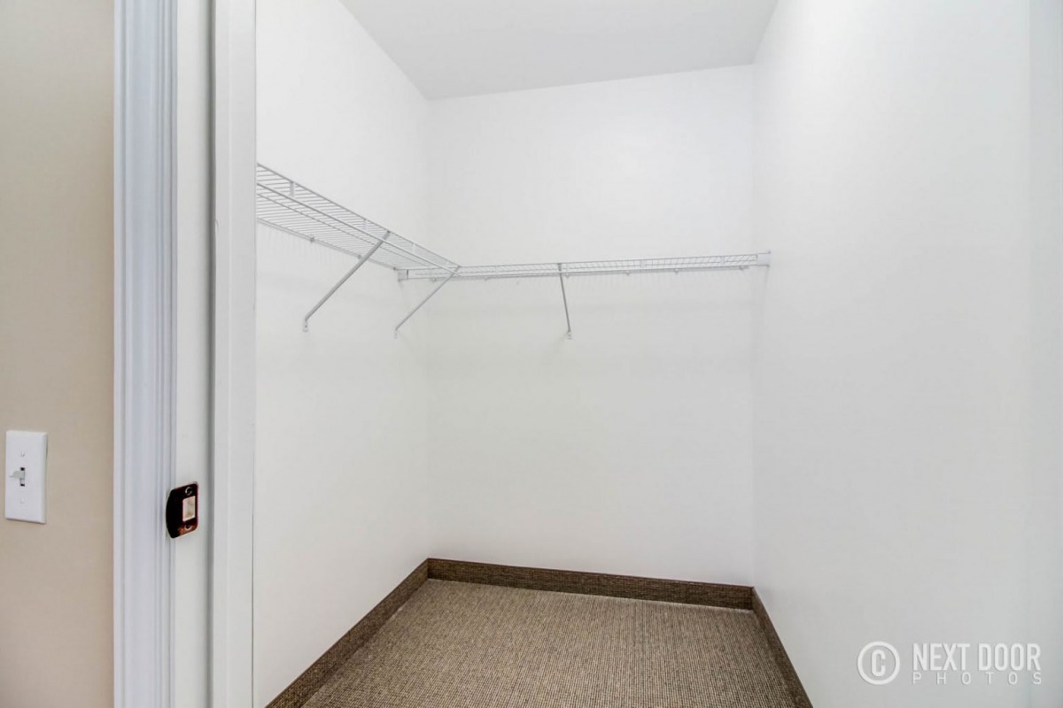 An empty walk-in closet with white walls and shelving.
