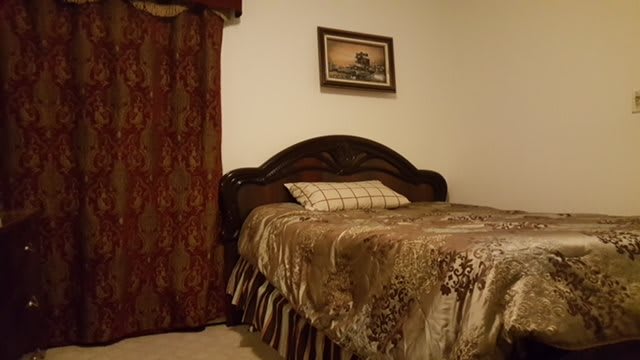 A cozy bedroom with a decorative bedspread, pillow, and elegant curtains.