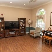 A cozy living room with a television stand, armchair, and piano.