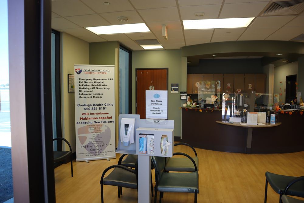 A medical clinic waiting room with seating and a reception desk.