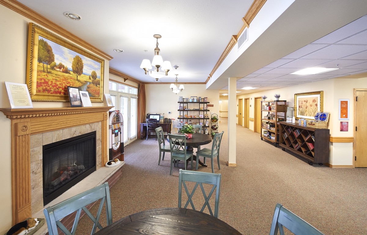 A cozy living and dining area featuring a fireplace, chandelier lighting, and wooden furniture.