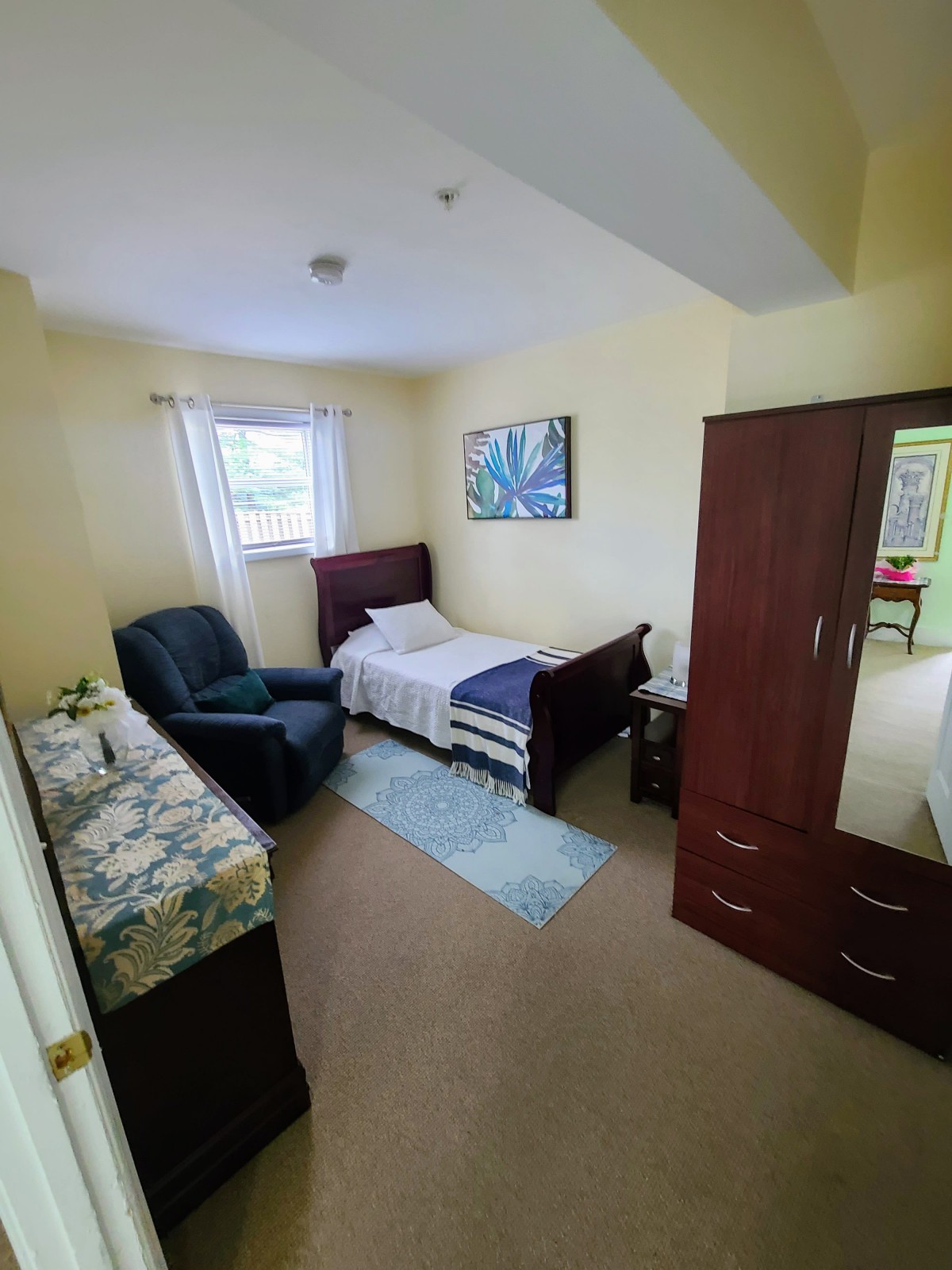 A cozy bedroom featuring a single bed, armchair, and wardrobe.