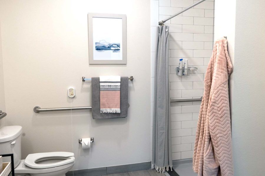 A clean and organized bathroom with a toilet, shower, and neatly hung towels.