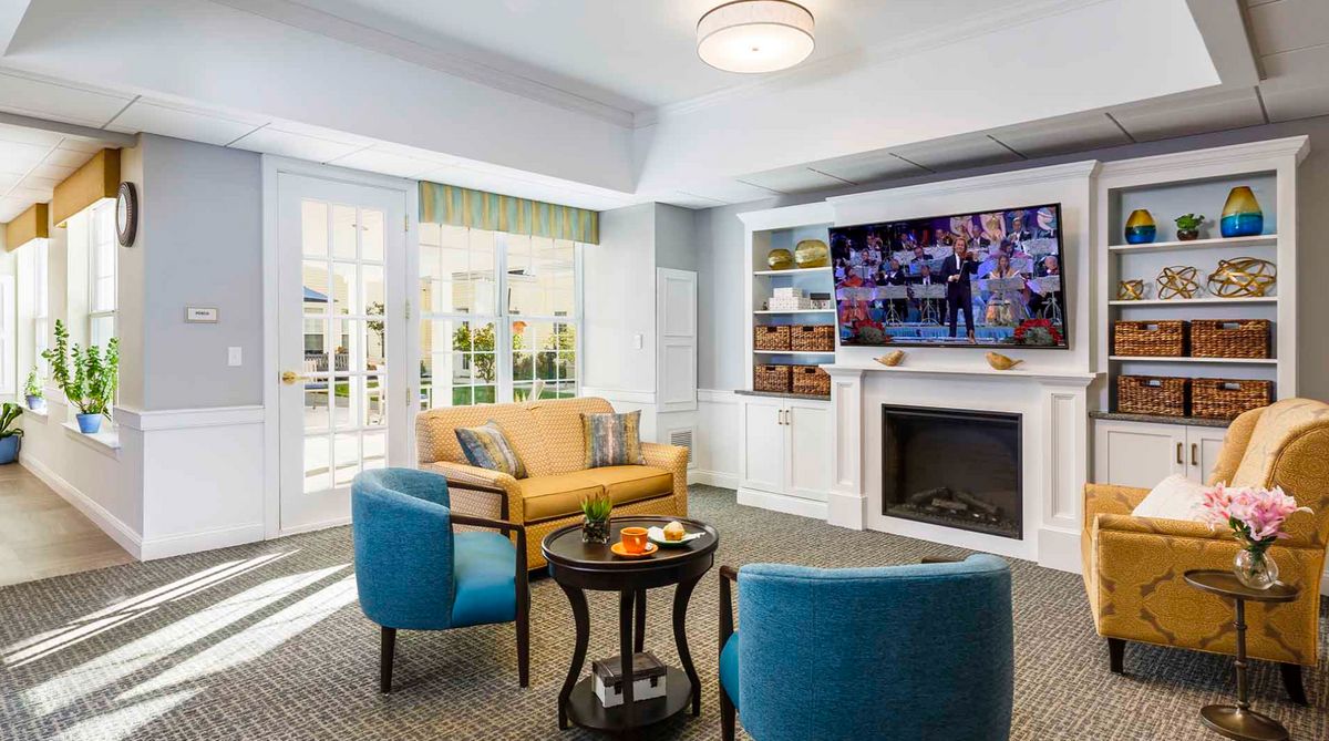 A modern living room with comfortable seating and a large television above the fireplace.