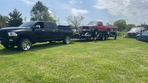 A black truck towing a red pickup on a sunny day.