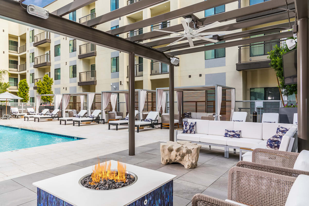 Modern outdoor lounge area with a fire pit, pool, and comfortable seating.