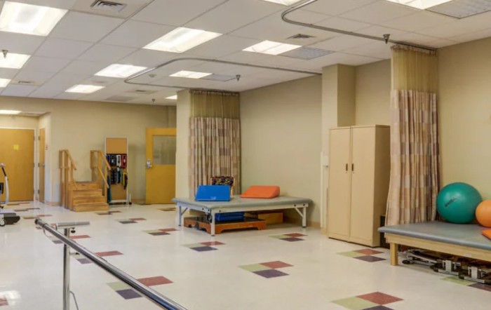 A spacious physical therapy room equipped with exercise tools and a therapy bed.