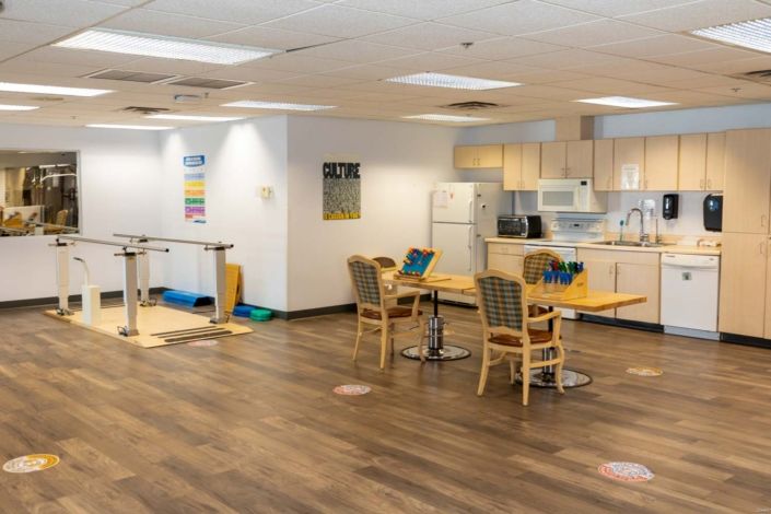 A rehabilitation center therapy room with a kitchen setup and exercise equipment.