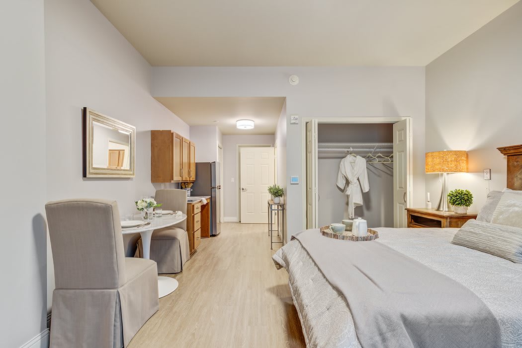 A cozy studio apartment featuring a modern bedroom with an open closet and a small dining area.