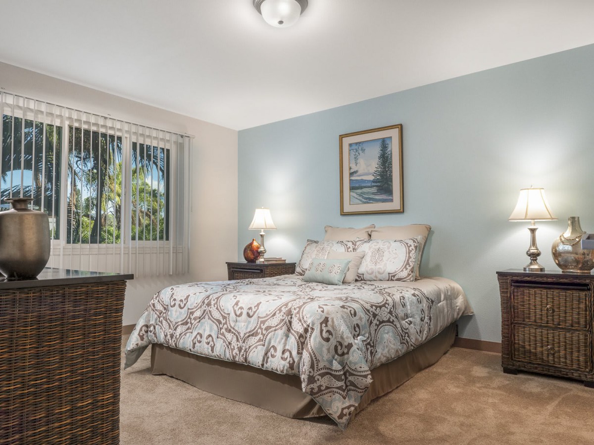 A cozy bedroom with a neatly made bed, two nightstands, and soft lighting.