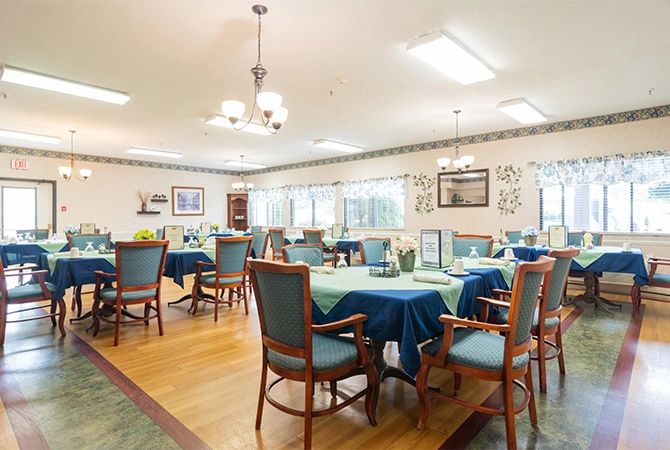 An inviting dining room with neatly set tables and comfortable chairs, illuminated by soft indoor lighting.