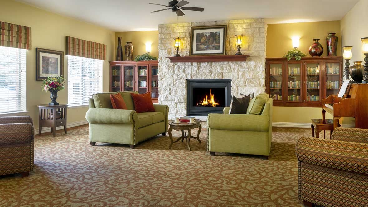 A cozy living room with a stone fireplace, comfortable seating, and warm lighting.
