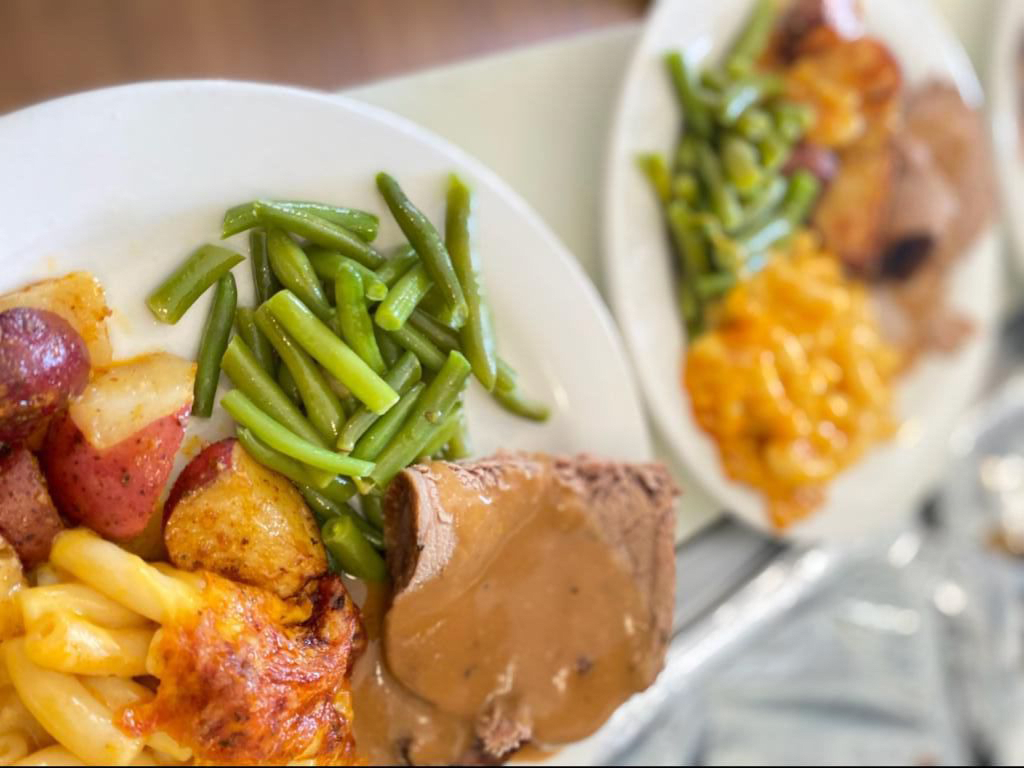 A hearty meal featuring meatloaf with gravy, green beans, and roasted potatoes.