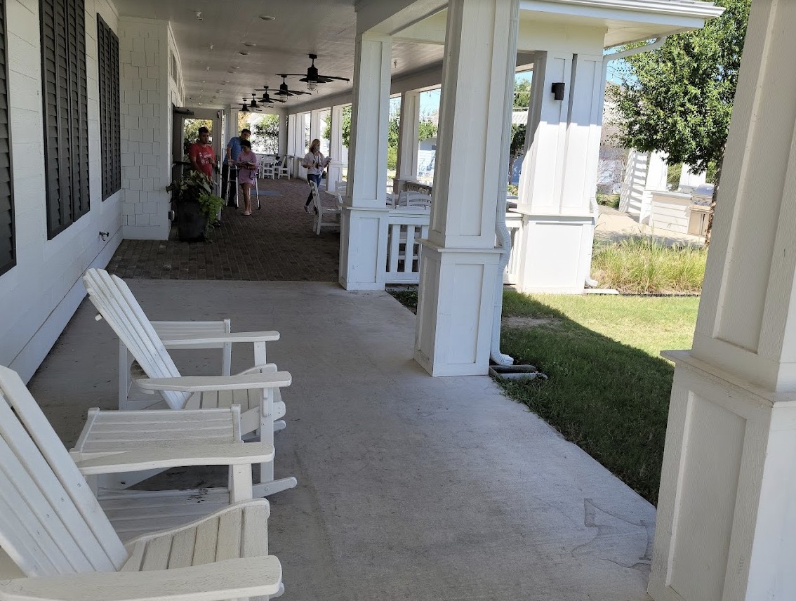 A large porch with white chairs and a view of the garden.