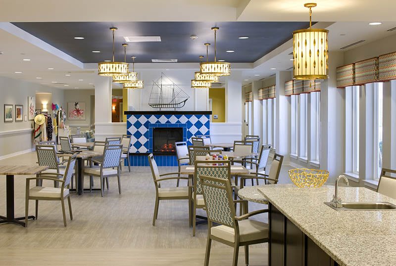 A modern dining area featuring elegant tables and chairs, with a central fireplace and stylish ceiling lights.