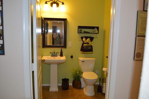 A cozy bathroom featuring green walls, a sink, and decorative accents.