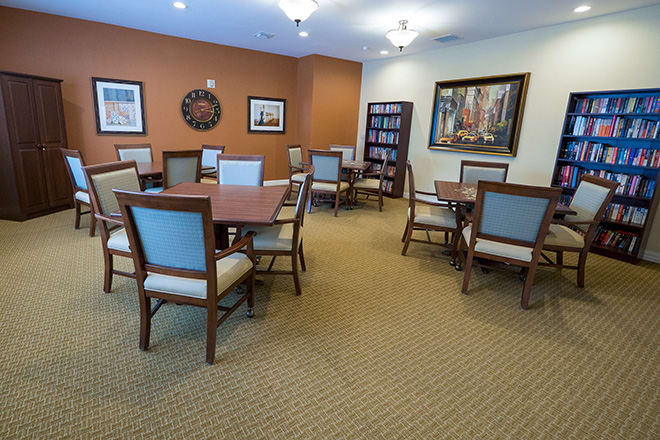 A quiet meeting room with tables and chairs, decorated with artwork and a bookshelf.