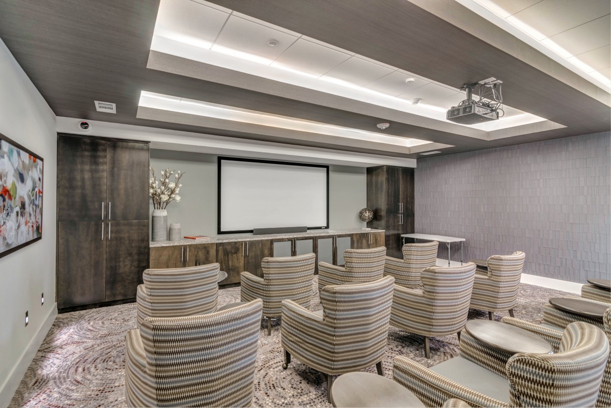 A modern conference room with comfortable seating and a projector screen for presentations.