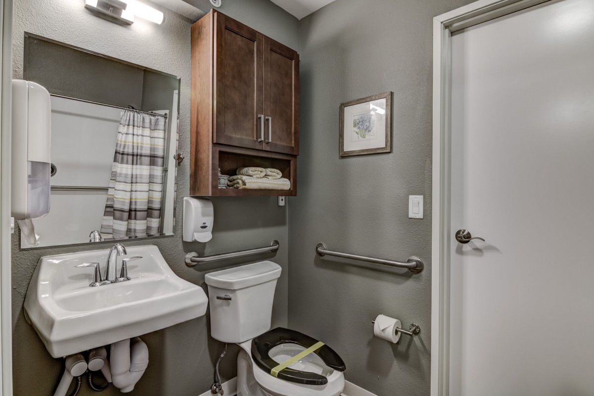 A modern bathroom with a sink, toilet, and wooden cabinet.