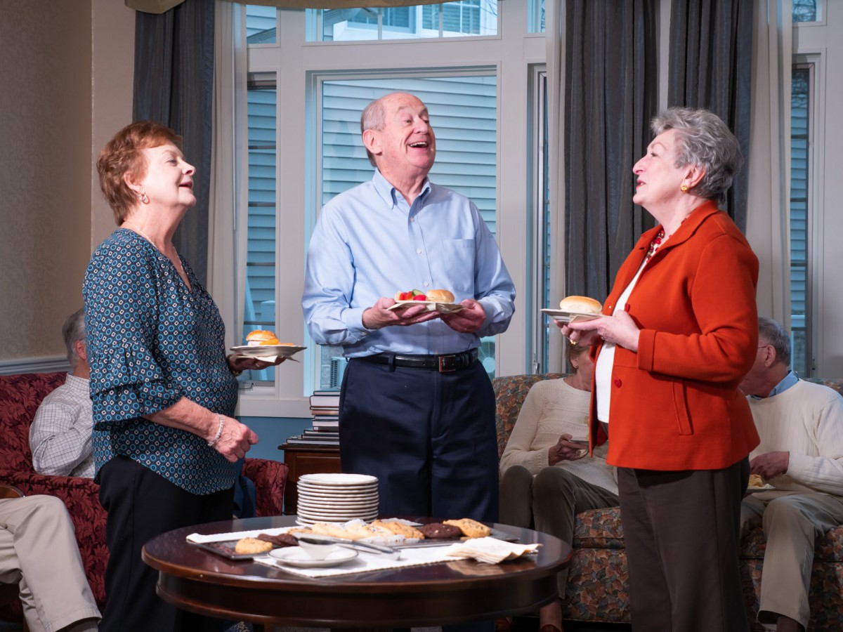 A group of elderly people enjoying a cheerful get-together with cakes indoors.