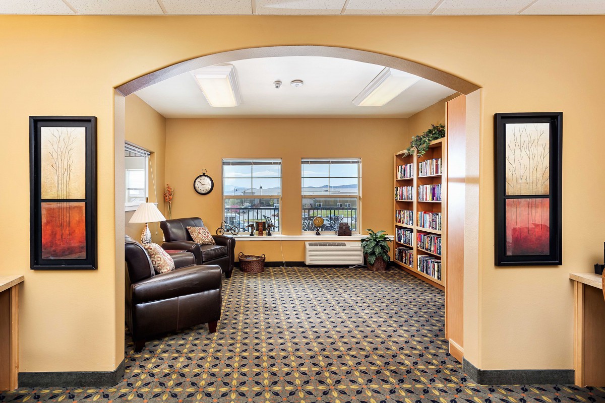 A cozy office waiting area with sofas, bookshelves, and large windows.