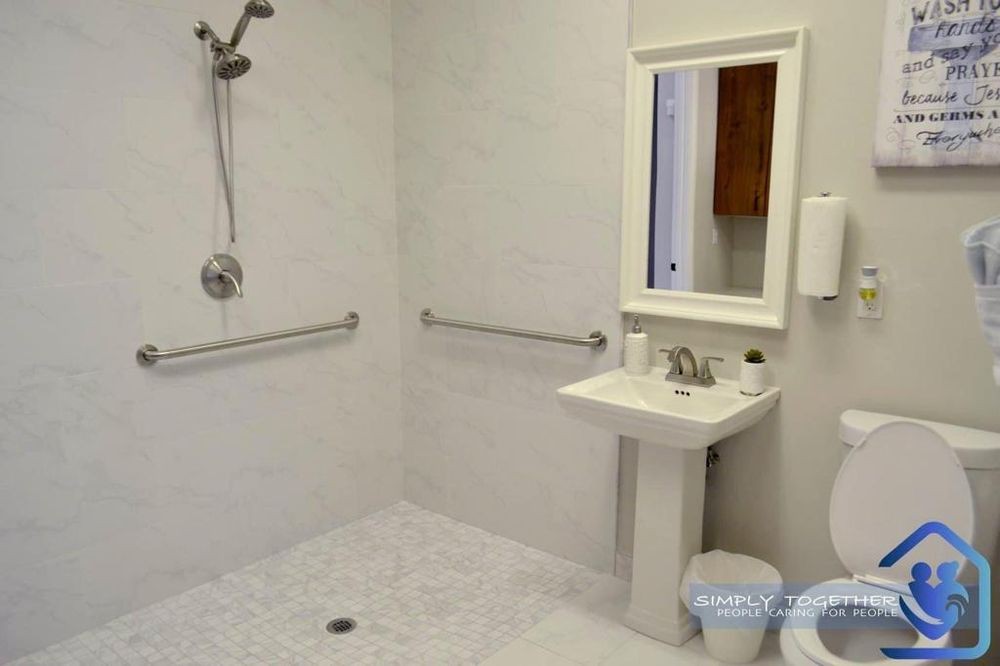 An accessible bathroom with a walk-in shower, sink, and safety grab bars.