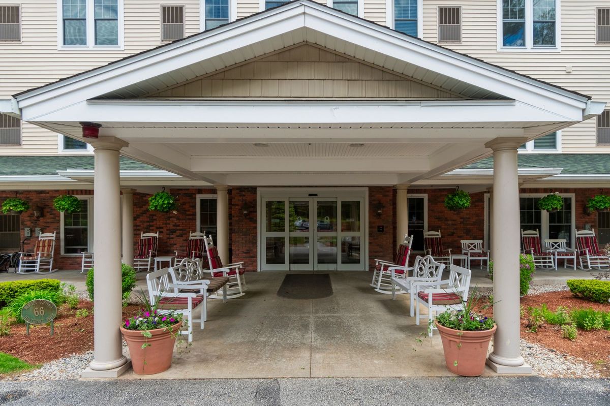 Front entrance of a building with rocking chairs and potted plants.