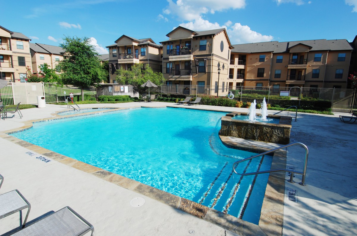 A luxurious apartment complex with a large outdoor swimming pool.