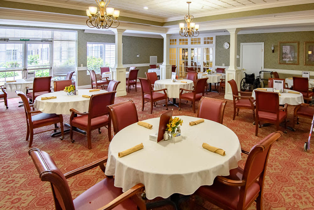 An elegant dining room with neatly arranged tables and chairs, adorned with chandeliers.