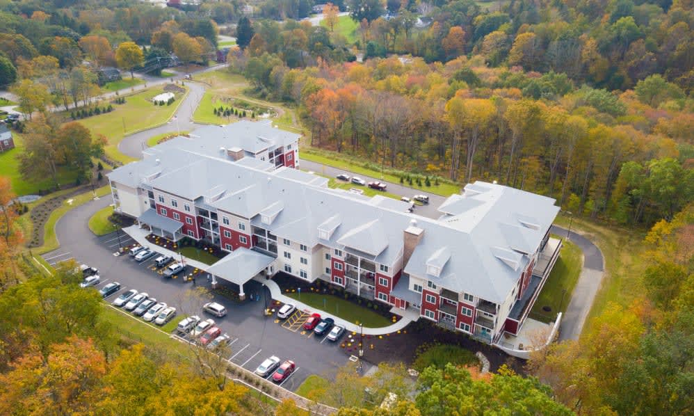 Aerial view of a residential building surrounded by autumn trees.