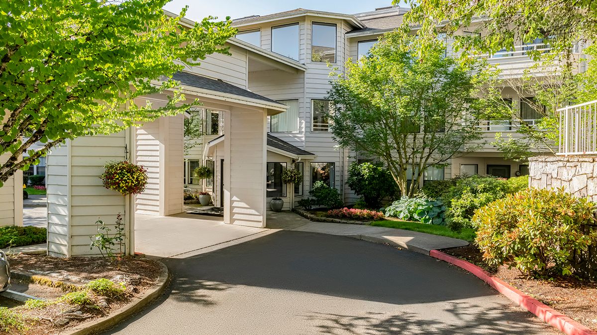 A residential building with a well-maintained driveway and lush landscaping.