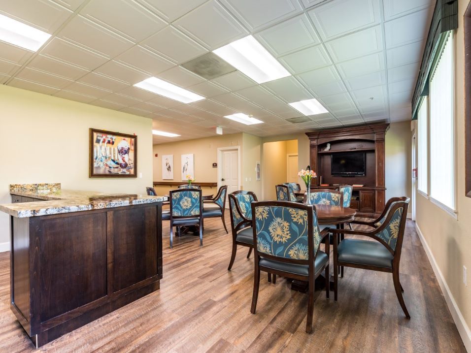 A well-lit dining area with elegant chairs and tables, featuring wood flooring and decorative artwork.