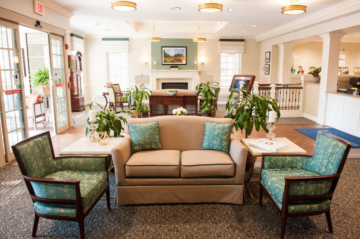 A cozy and well-decorated living room featuring a sofa, armchairs, plants, and ample natural light.