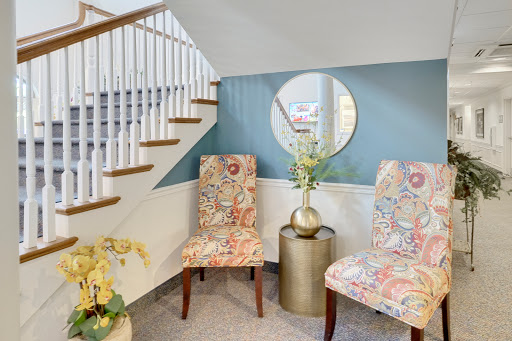 A stylish and inviting seating area featuring two upholstered chairs, a circular mirror, and decorative elements.