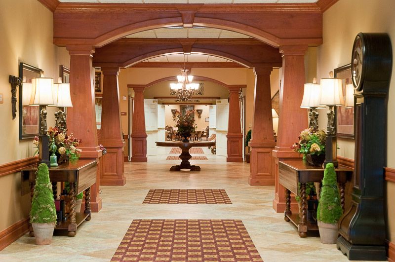 A luxurious hotel lobby featuring classical wood accents and a central chandelier.