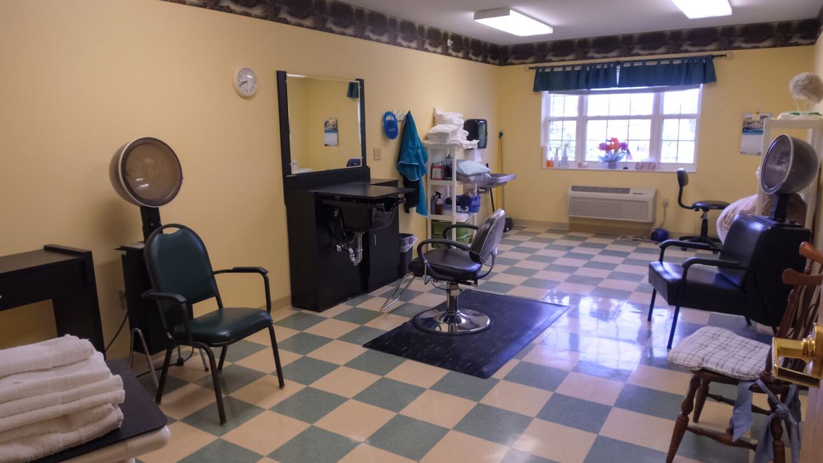 An empty hair salon with a checkered floor and a barber chair in front of a mirror.