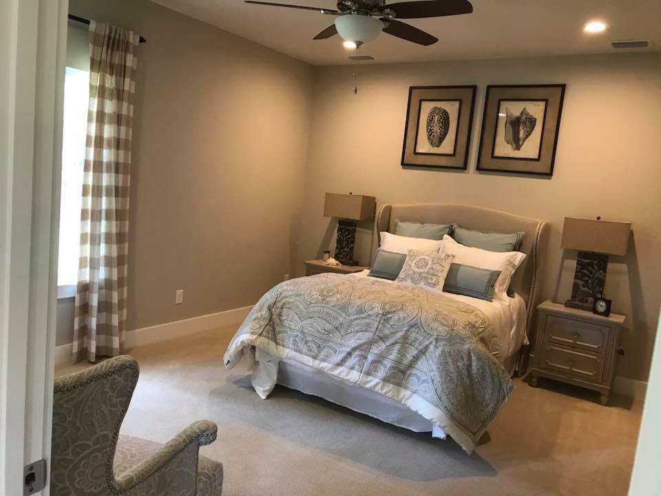 A cozy and well-decorated bedroom with neutral tones, featuring a comfortable bed, matching lamps, and plaid curtains.
