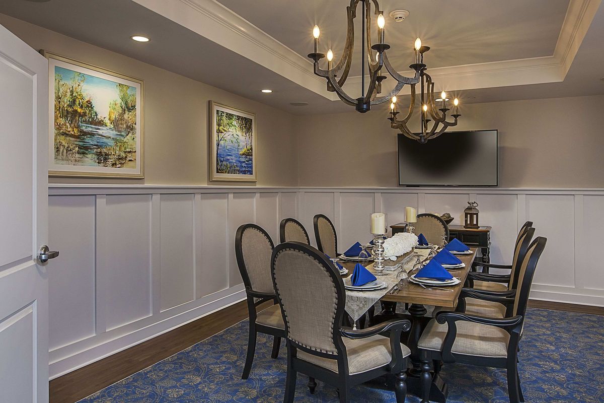 A well-decorated dining room with elegant chandeliers and a formal table setting.