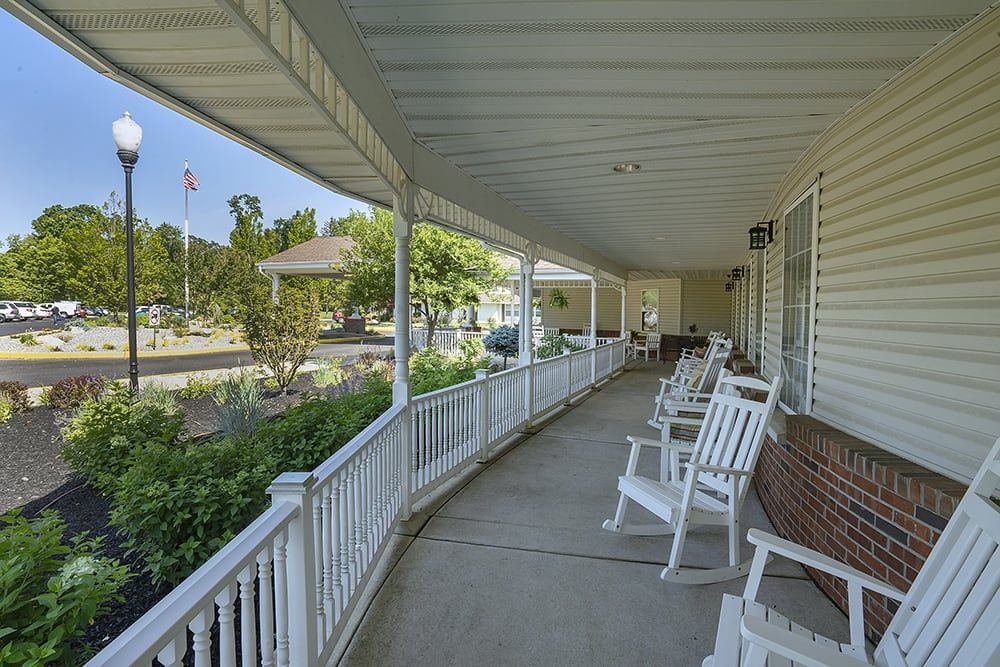 A peaceful covered porch with white rocking chairs overlooking a garden.