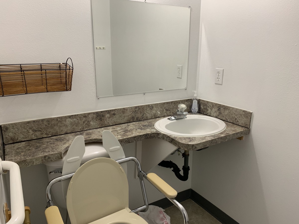 A minimalist bathroom setup with a wall-mounted sink and chair.