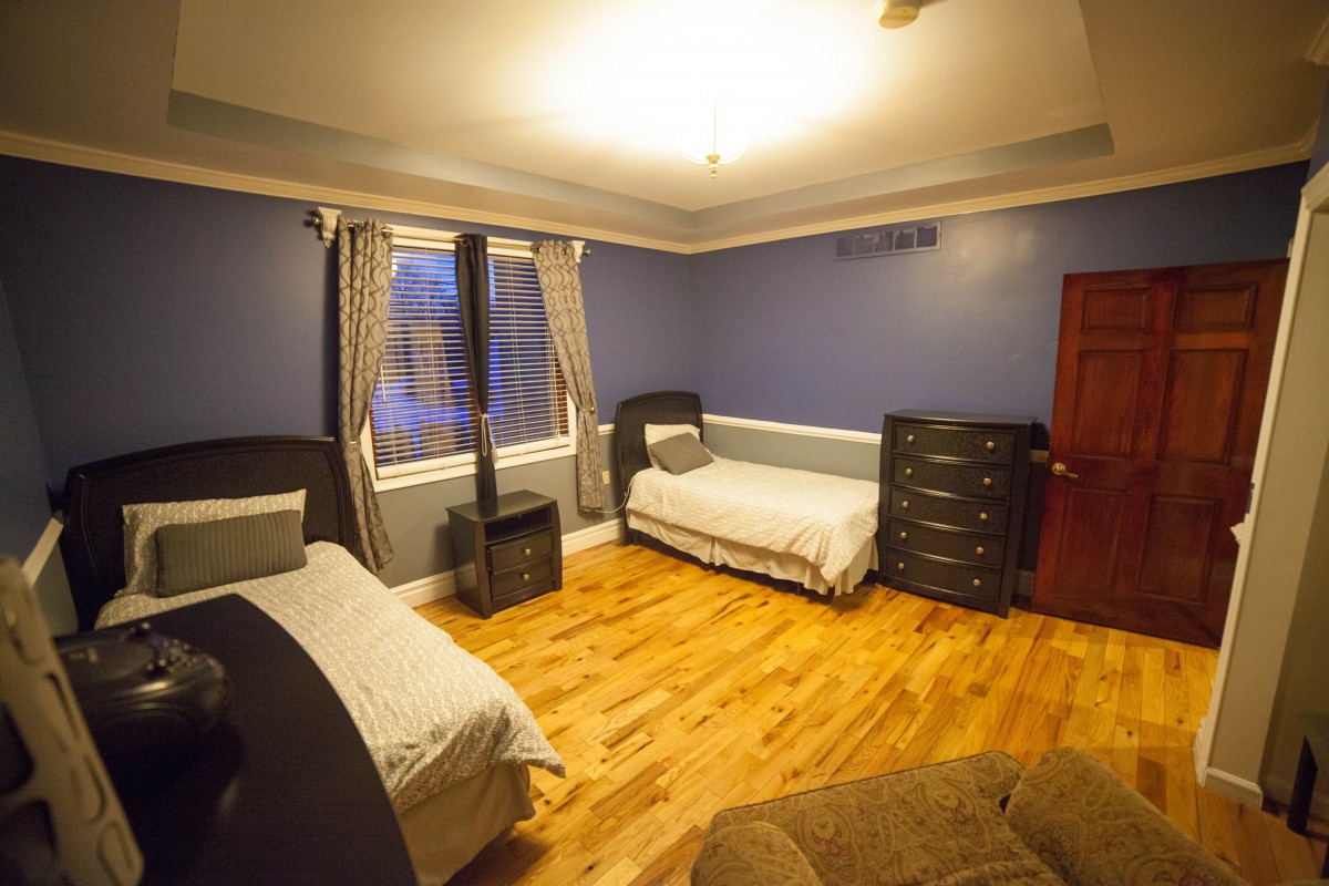 A cozy bedroom with two single beds, featuring blue walls and a hardwood floor.