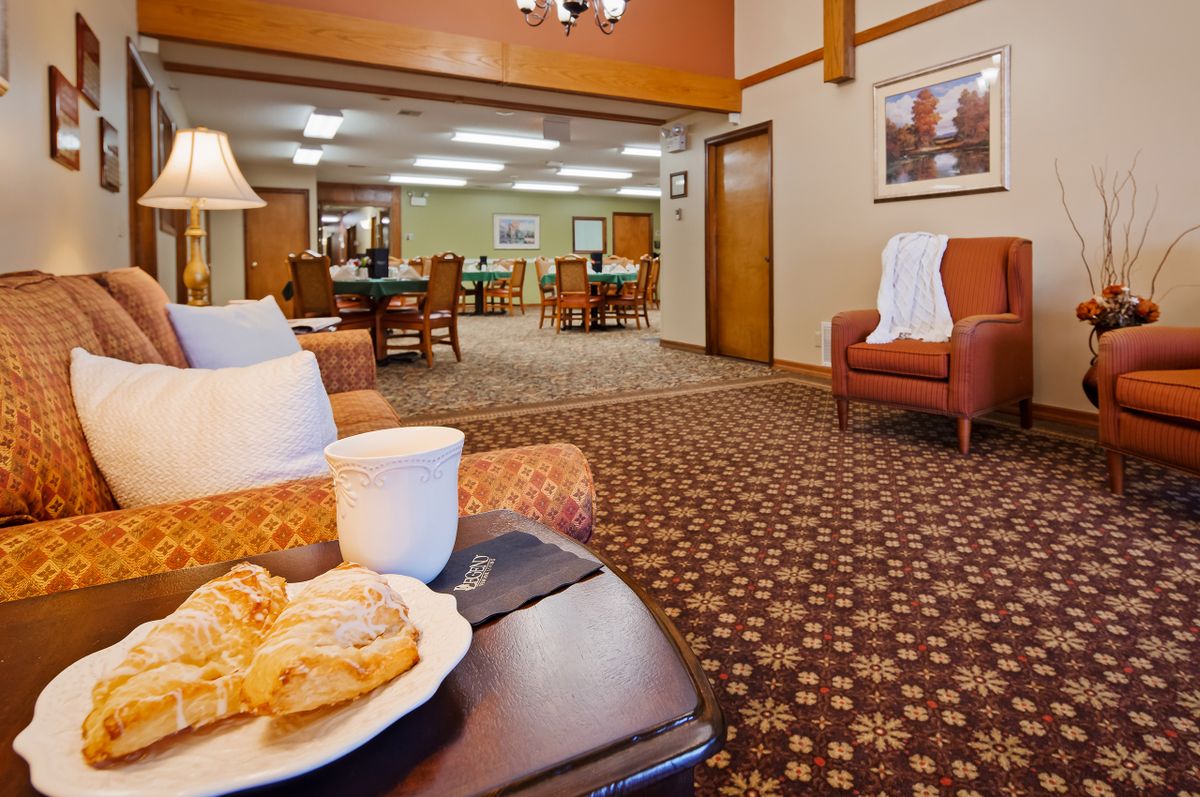 A cozy hotel lobby featuring comfortable seating areas with a plate of pastries and a cup of coffee in the foreground.