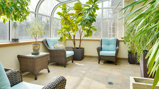 A bright and inviting sunroom featuring comfortable seating, lush greenery, and abundant natural light.