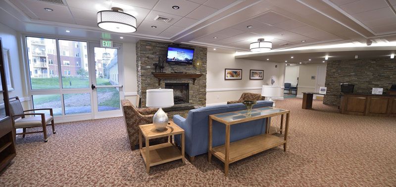 A cozy living room with a stone fireplace, comfortable seating, and a mounted television.