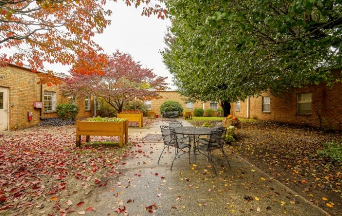 A peaceful courtyard with autumn foliage and outdoor seating.