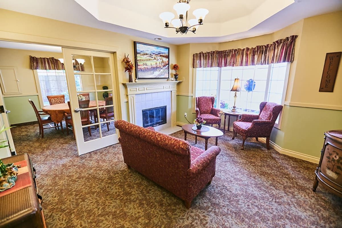 Cozy living room with a fireplace, sofa, and chairs near large windows.